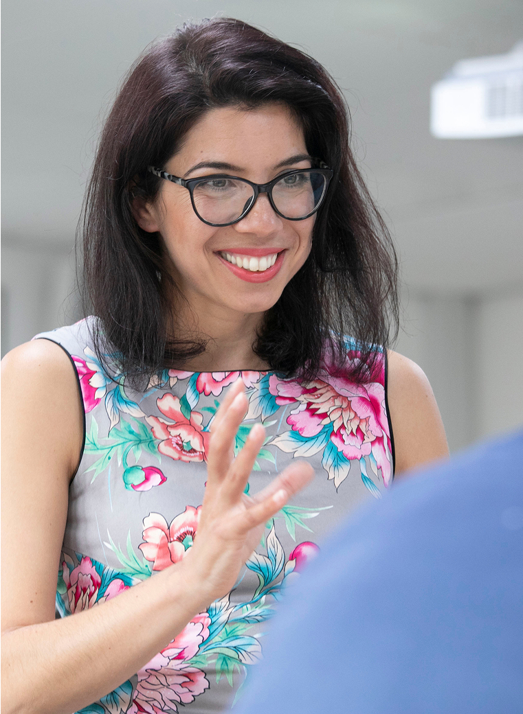 Daniela Bultoc engaging in a collaborative conversation during a professional session, wearing a floral dress and smiling while leaning toward a participant.
